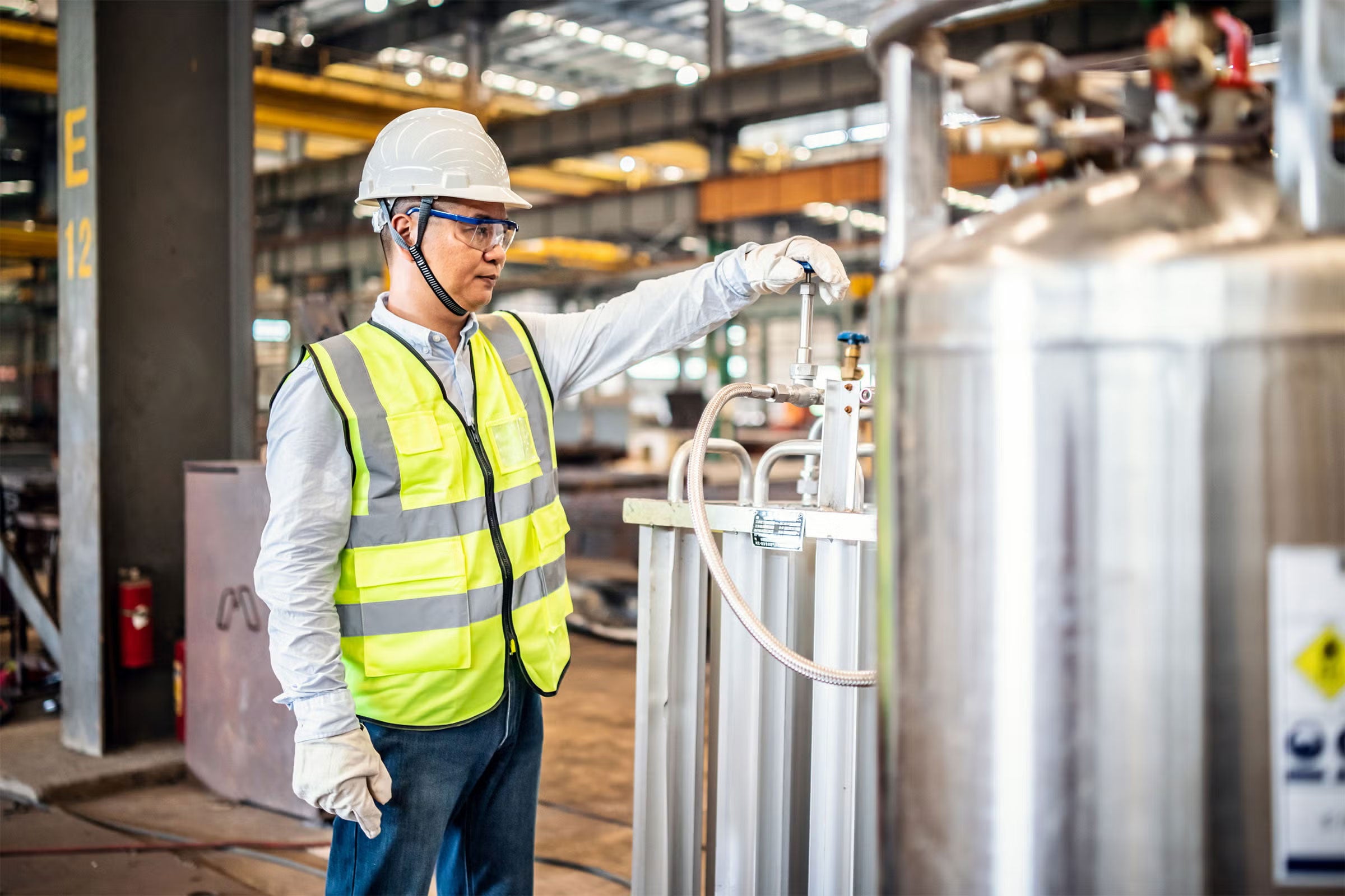 A worker operating a gas tank in a factory