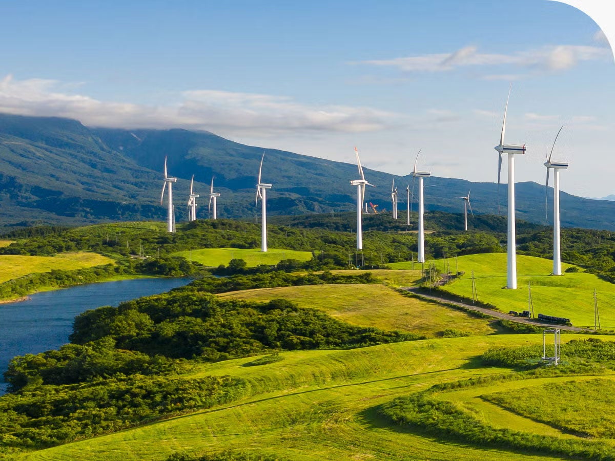 Wind turbines in a green field with mountains in the background