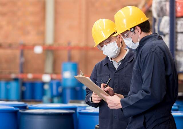 Two employees having a discussion and looking at a chart in a chemical plant