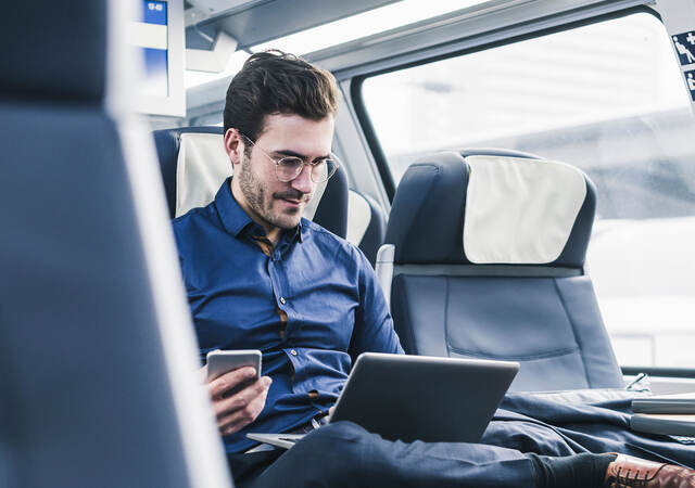 A person on public transit watching an on-demand webinar on a laptop