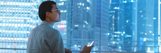 Man siting on roof of building holding smartphone