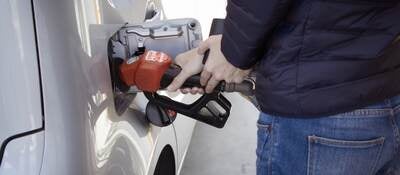 Man at a gas station pumping up his car with fuel