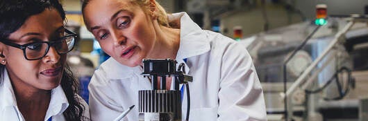 Two female medical engineers looking at test results