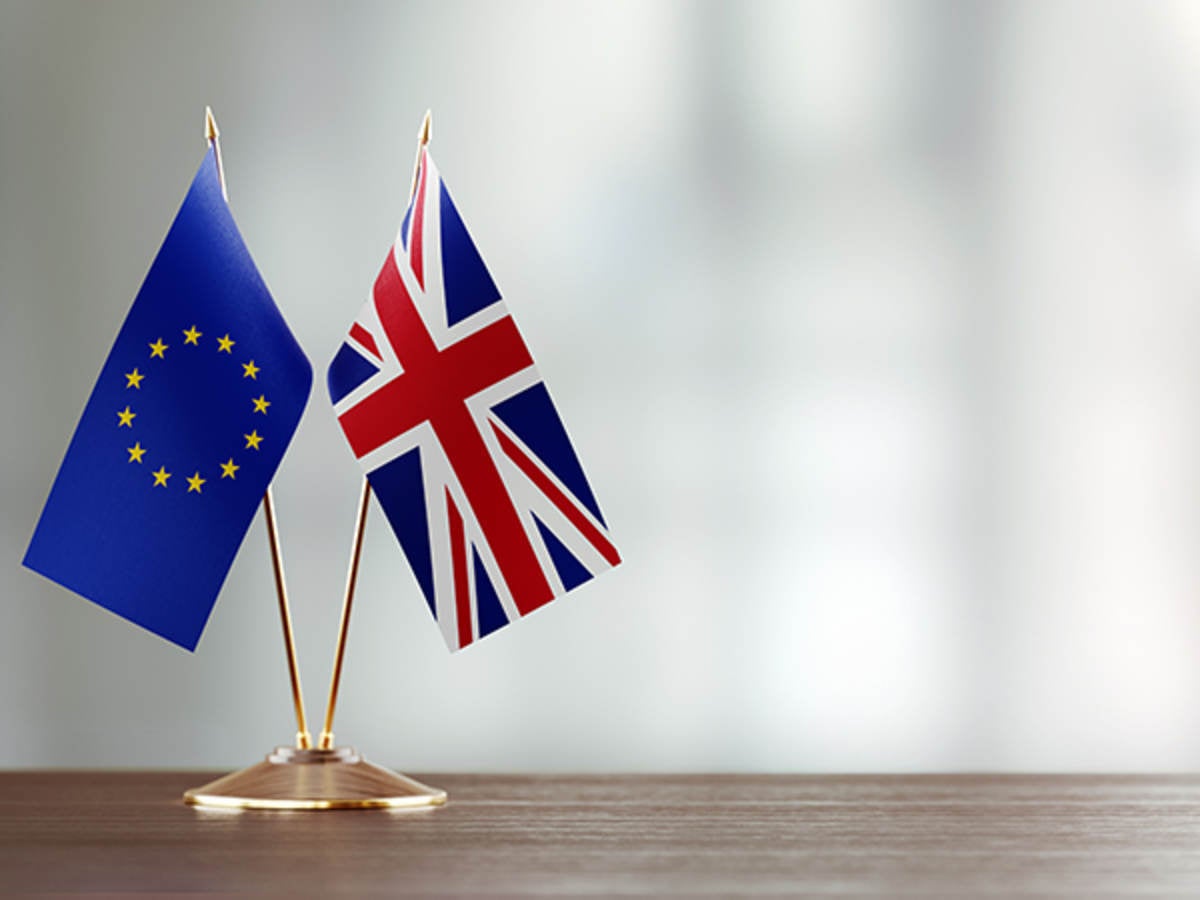 European-Union-And-British-Flag-Pair-On-A-Desk-Over-Defocused-Background