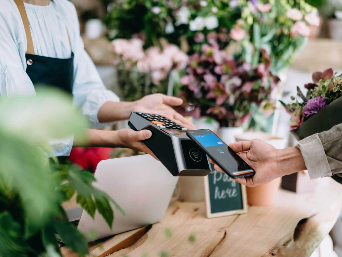Man paying for a bouquet of flowers with his smartphone using contactless payment. 