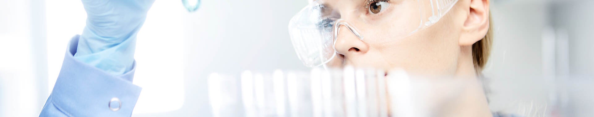 Woman looking at a test tube of solution in a lab